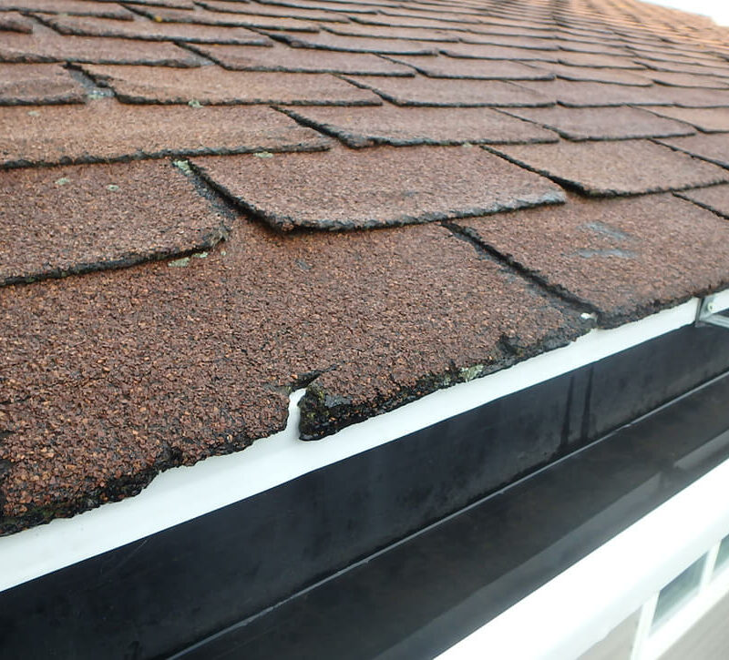 closeup of damaged shingles on edge of home's roof