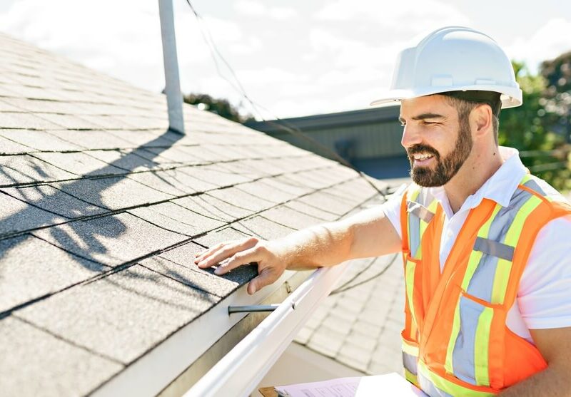 roofing contractor with clipboard making notes about a roof